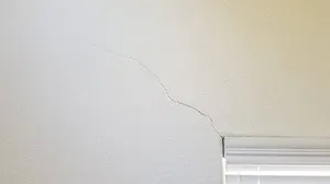 hairline wall crack above window